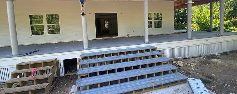Covered porch with columns and multi-level composite stairs under construction