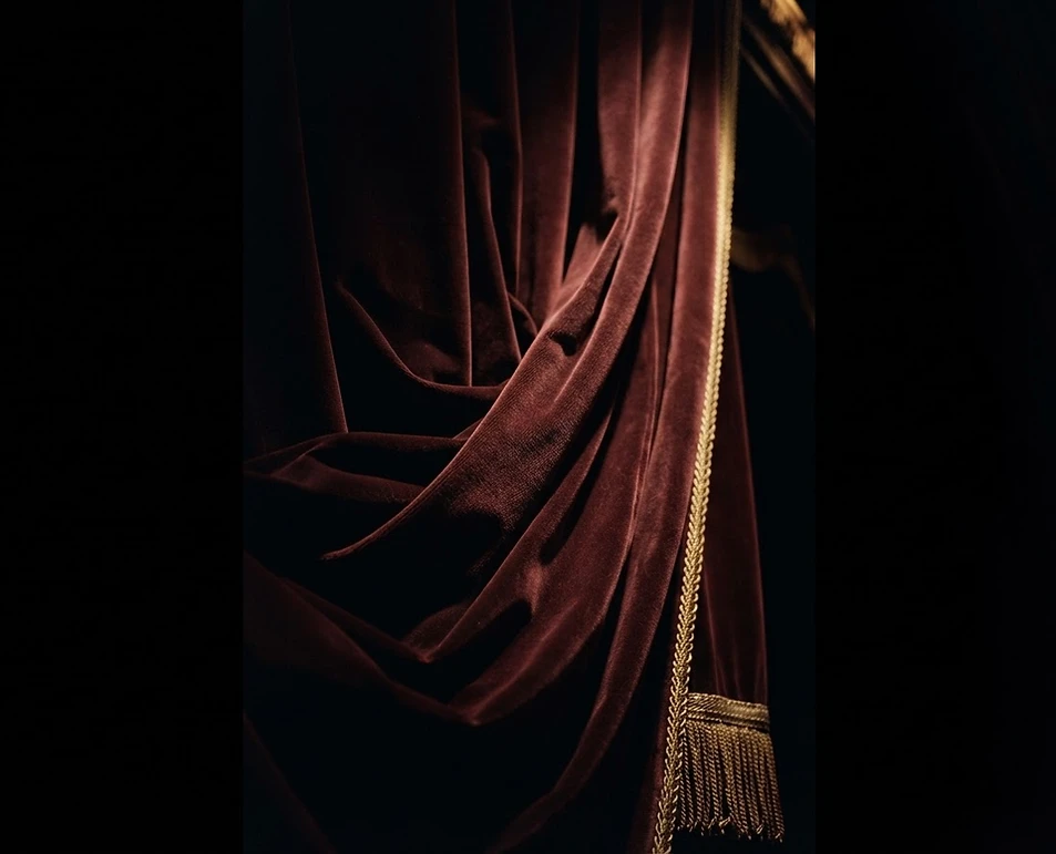 Oxblood theatre curtain in dramatic light