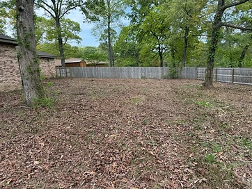 Mulched backyard along a fence line after a property cleanup