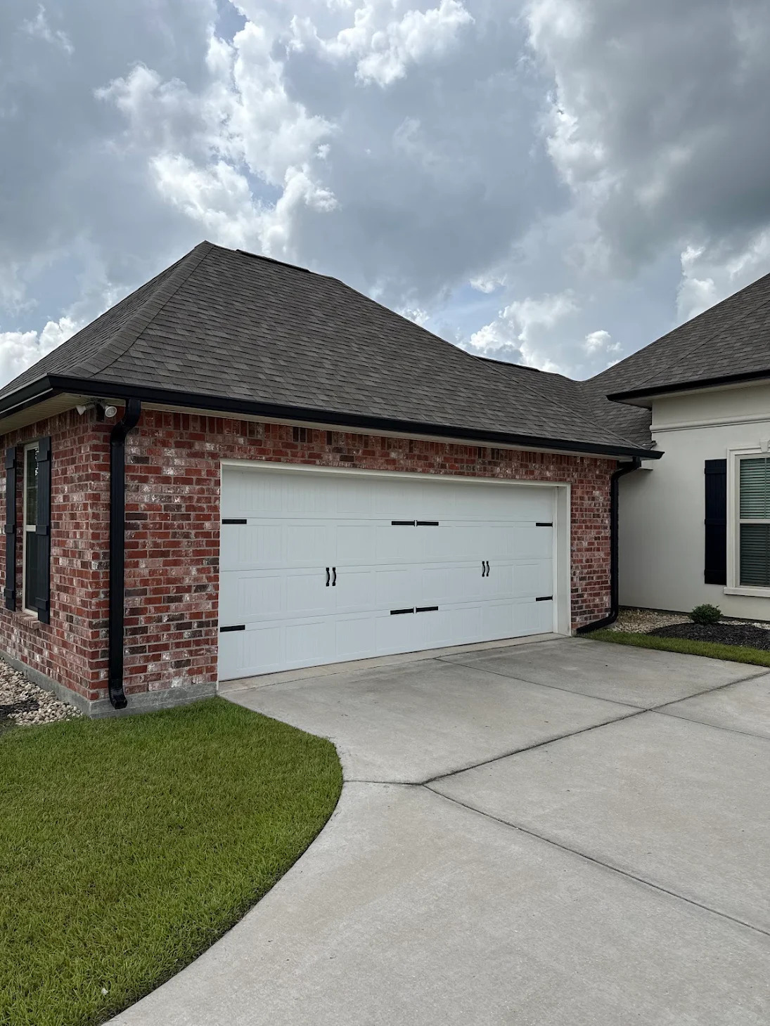 Black seamless gutters and downspouts on a brick garage