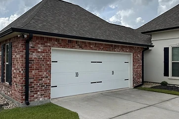 Black seamless gutters and downspouts on a brick garage