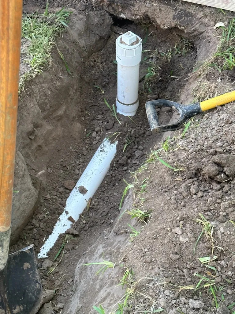 Trench with buried downspout drain pipe and pop-up emitter