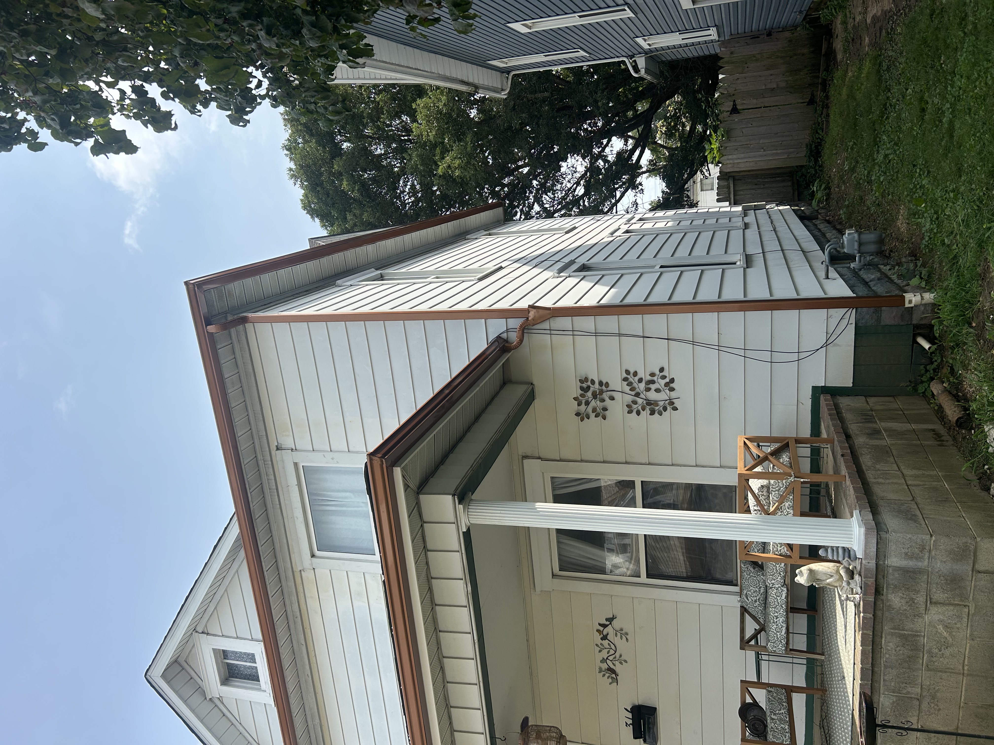 Copper-tone gutter and downspout on a white-sided home