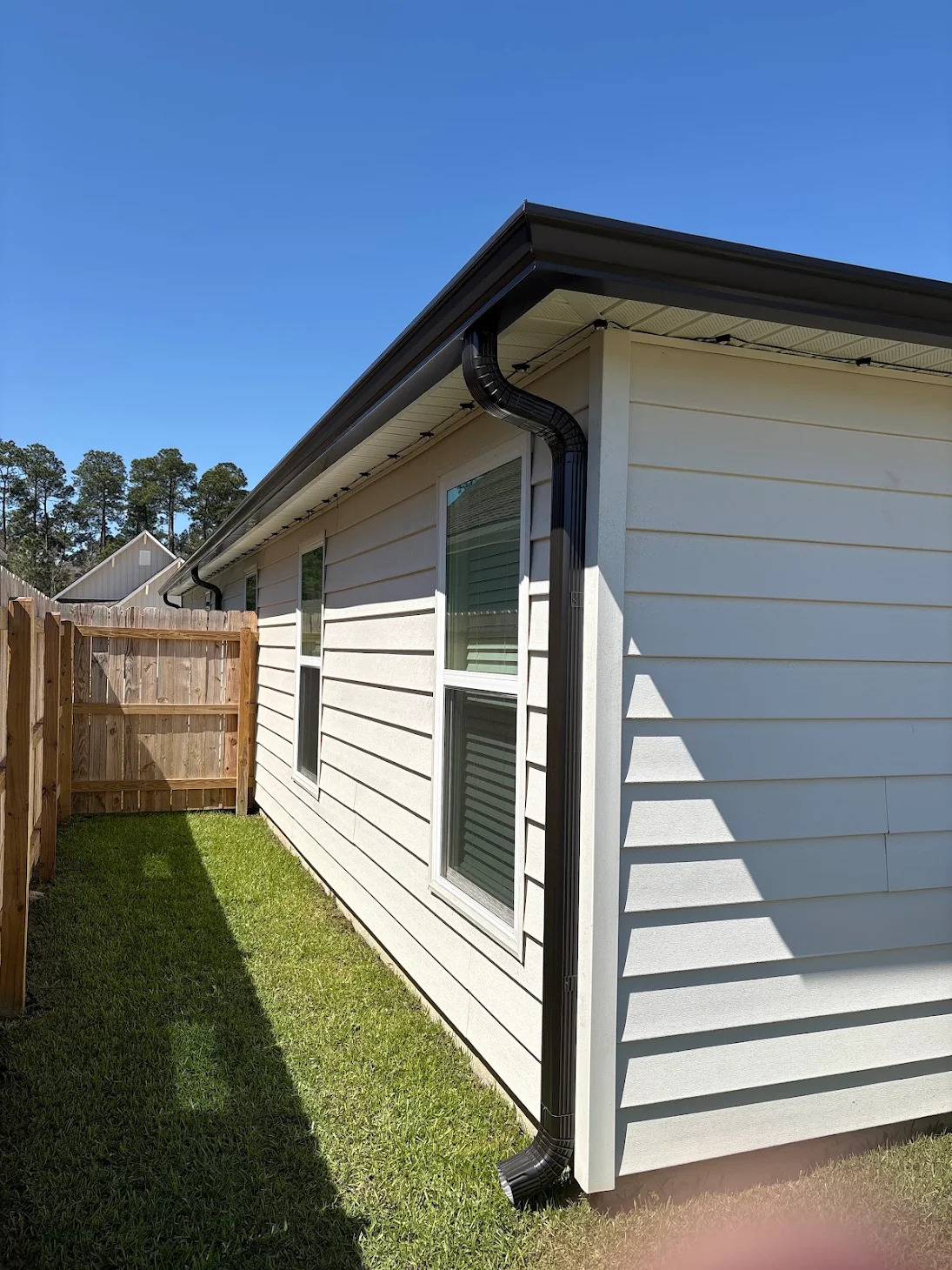 Black downspout along white lap siding