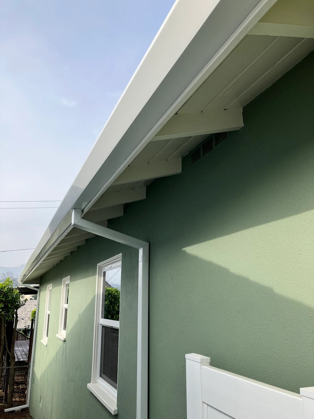 White gutter and downspout on a green stucco home