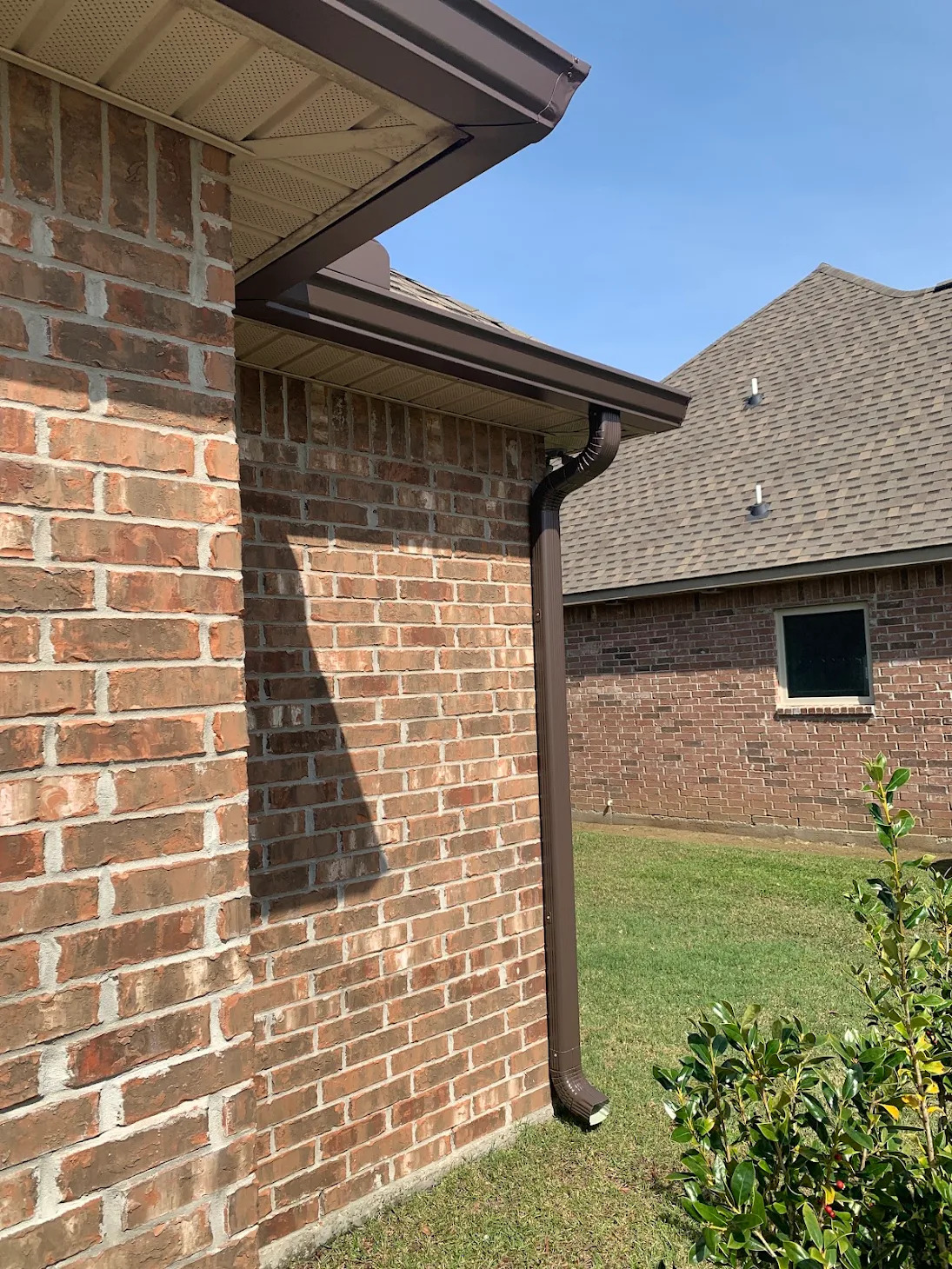 Brown gutter and downspout on a brick home