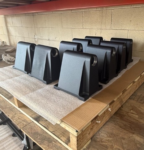 Finished black powder-coated brackets arranged on a pallet at ICG