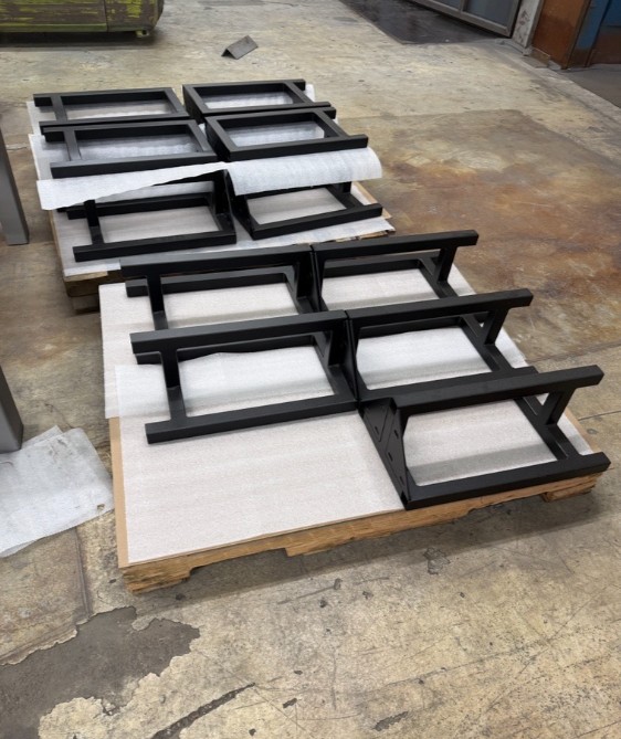 Black powder-coated fabrication components on a pallet at ICG