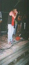 Performer in a red feather boa singing on the wooden stage at JescoFest 2006