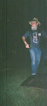 Bearded cowboy in a Hank Williams hat standing by the stage platform at night at JescoFest 2006