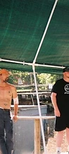 Three men posing on the wooden stage under the green canopy at JescoFest 2006