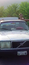 Festival attendees gathered around a white Volvo sedan on a gravel road at JescoFest 2006