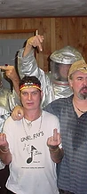 8-BIT in silver fire-entry suits posing with friends against a wood-paneled wall at JescoFest 2006