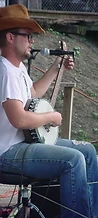 J. Glenn playing banjo in profile on the wooden stage at JescoFest 2006
