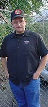 Man in a Hank Williams Jr cap and Lucky 13 shirt posing by a chain-link fence at JescoFest 2006