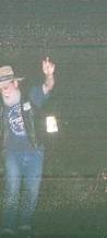 Bearded cowboy pointing upward with a Bud Light on the stage at night at JescoFest 2006