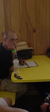 Four men sitting around a yellow table inside a wood-paneled room at JescoFest 2006