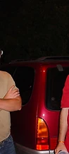 Three men posing by a maroon minivan at night at JescoFest