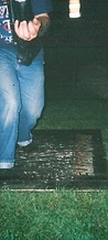 Bearded cowboy in a Hank Williams hat stepping onto the wooden platform at night at JescoFest 2006