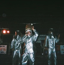8-BIT performing on stage in silver fire suits with JescoFest banners at night at JescoFest 2006