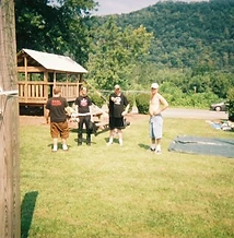 Four men posing in the grass by the wooden pavilion at JescoFest 2006