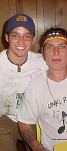 Two men flashing peace signs in front of wood-paneled walls at JescoFest 2006