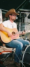 Musician in a cowboy hat playing a sunburst acoustic guitar on stage at JescoFest 2006