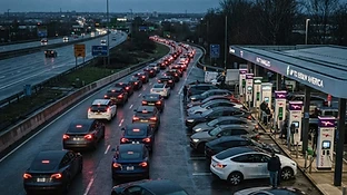 Long queue of electric vehicles waiting at charging stations