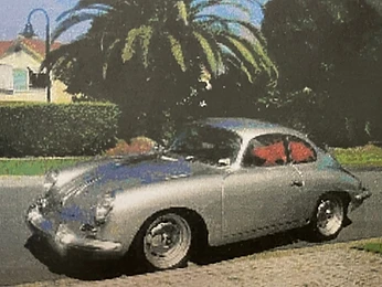 Classic silver sports car parked in front of a palm tree