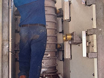 Worker reaching up to assemble a ribbed vertical column inside a metal frame