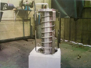 Stainless steel heat exchanger coil on a pedestal in a workshop