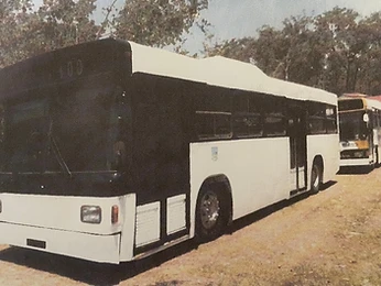 Two buses parked on a dirt lot