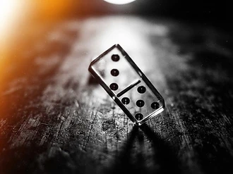 Glass domino mid-topple under hard light