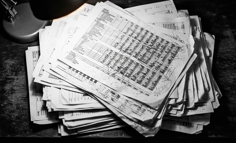 Stacked financial documents under a harsh desk lamp