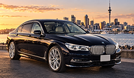 A black BMW 750Li on the Auckland waterfront at sunset