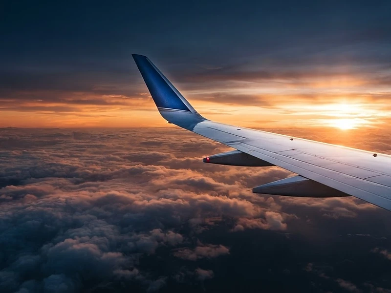 Business jet wing slicing through a sunset cloud layer at altitude