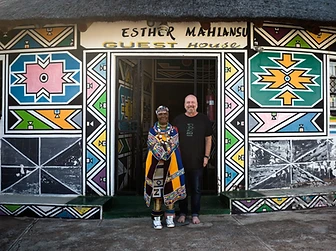 Full-length portrait of Esther Mahlangu with Craig Mark, director of The Melrose Gallery, at the Esther Mahlangu Guest House, by Clint Strydom