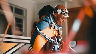 Esther Mahlangu painting a geometric canvas, in profile