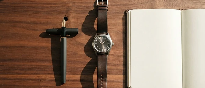 Minimalist desk with watch, fountain pen and notebook