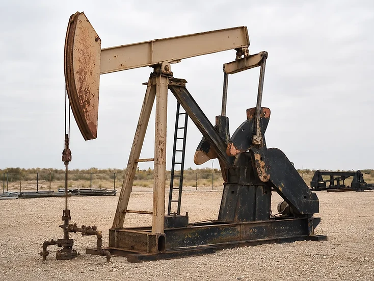 Oilfield pumping unit on a gravel lot under an overcast sky.