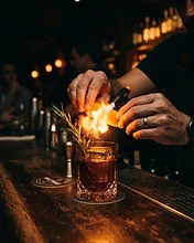 Bartender garnishing with flamed orange peel