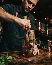 Bartender muddling fresh fruit and herbs