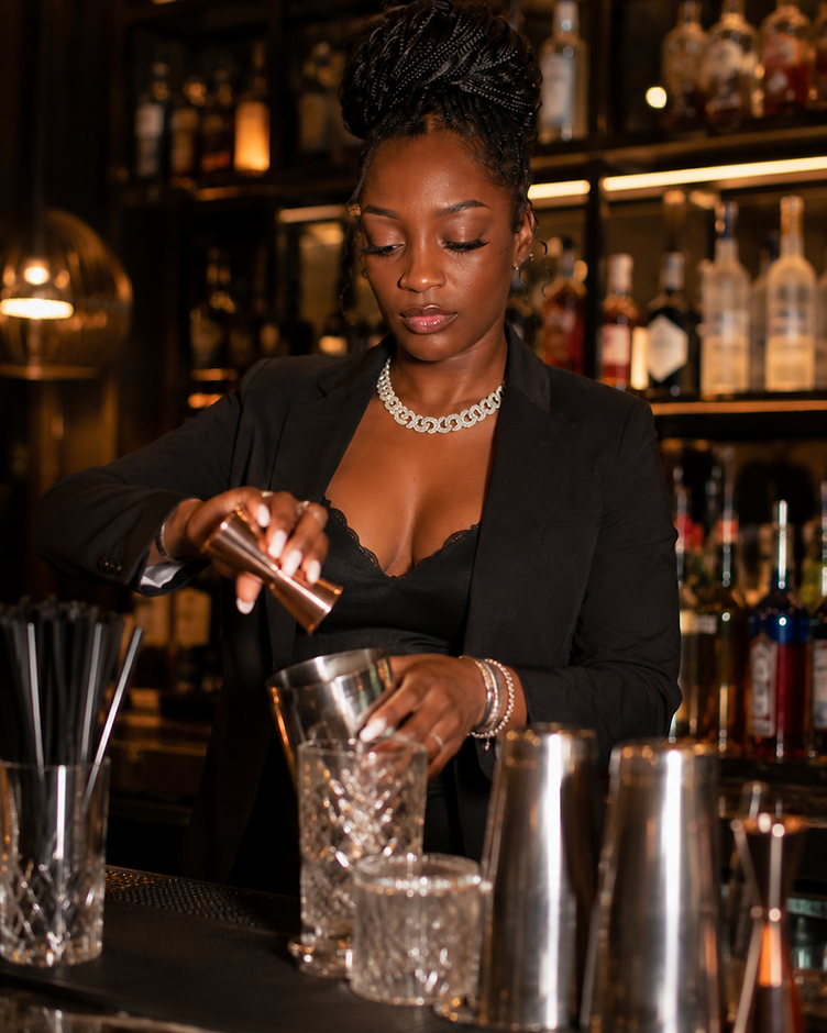 Janee Jackson pouring from a copper jigger behind the bar