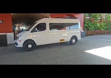 White passenger van side profile at a hotel entrance
