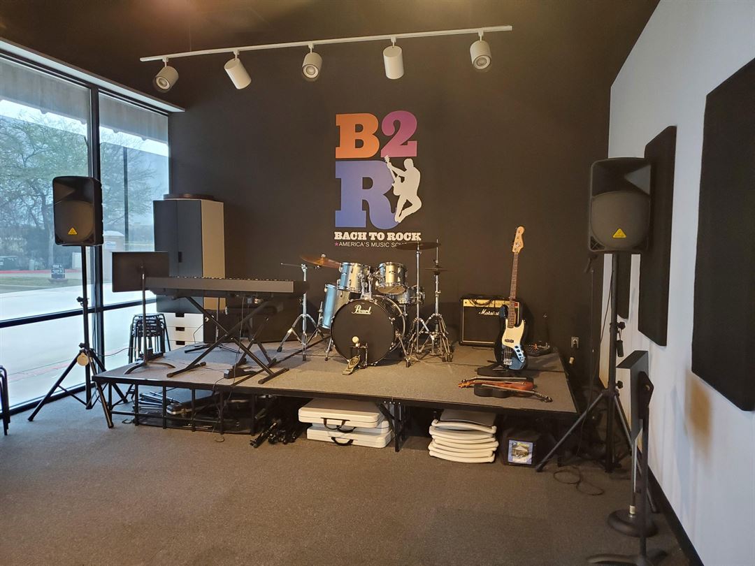 Finished music school interior with an elevated performance stage, instruments and acoustic treatment