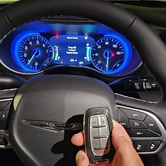 Car key fob held in front of digital instrument cluster