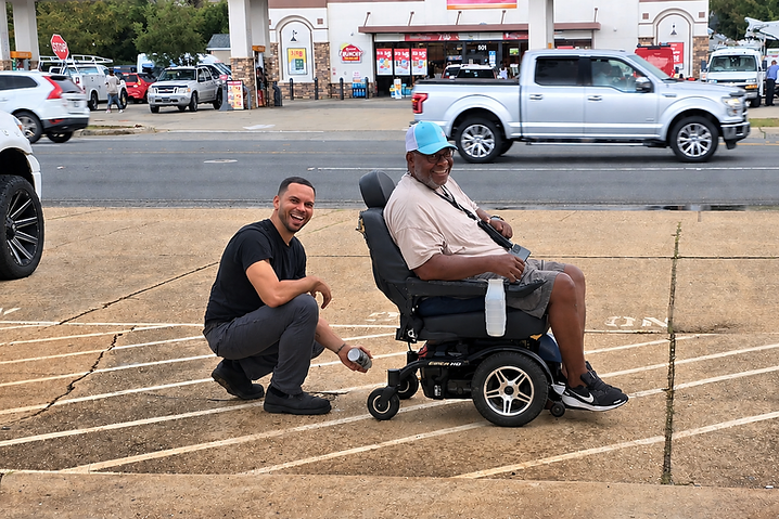 Fernando Nando Núñez helping a community member with a motorized mobility chair.