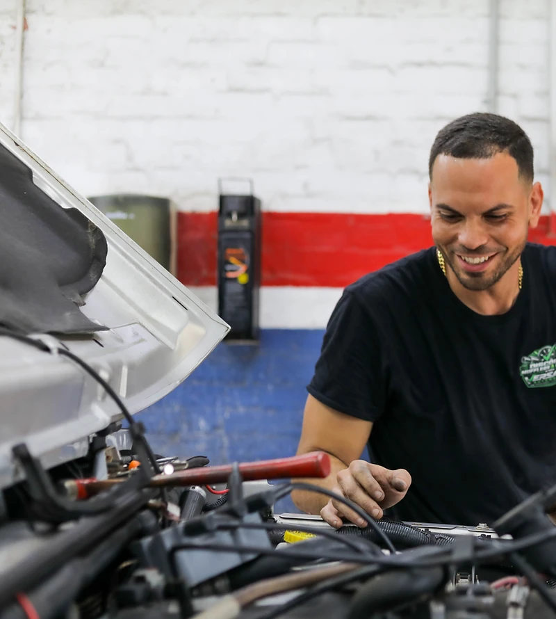 Versatile Automotive technician performing under-hood service at the Pensacola shop