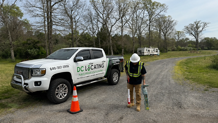 DC Locating technician scanning a site with a utility locating device beside a branded truck