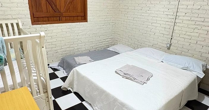 Quarto com cama de casal, berço e piso quadriculado